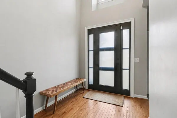 a view of an empty room with window and hardwood floor