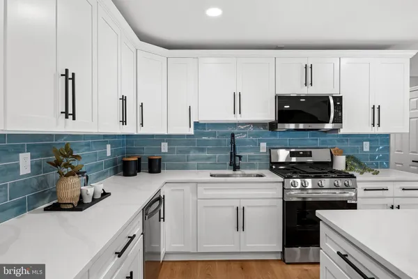 a kitchen with a sink stove and wooden floor
