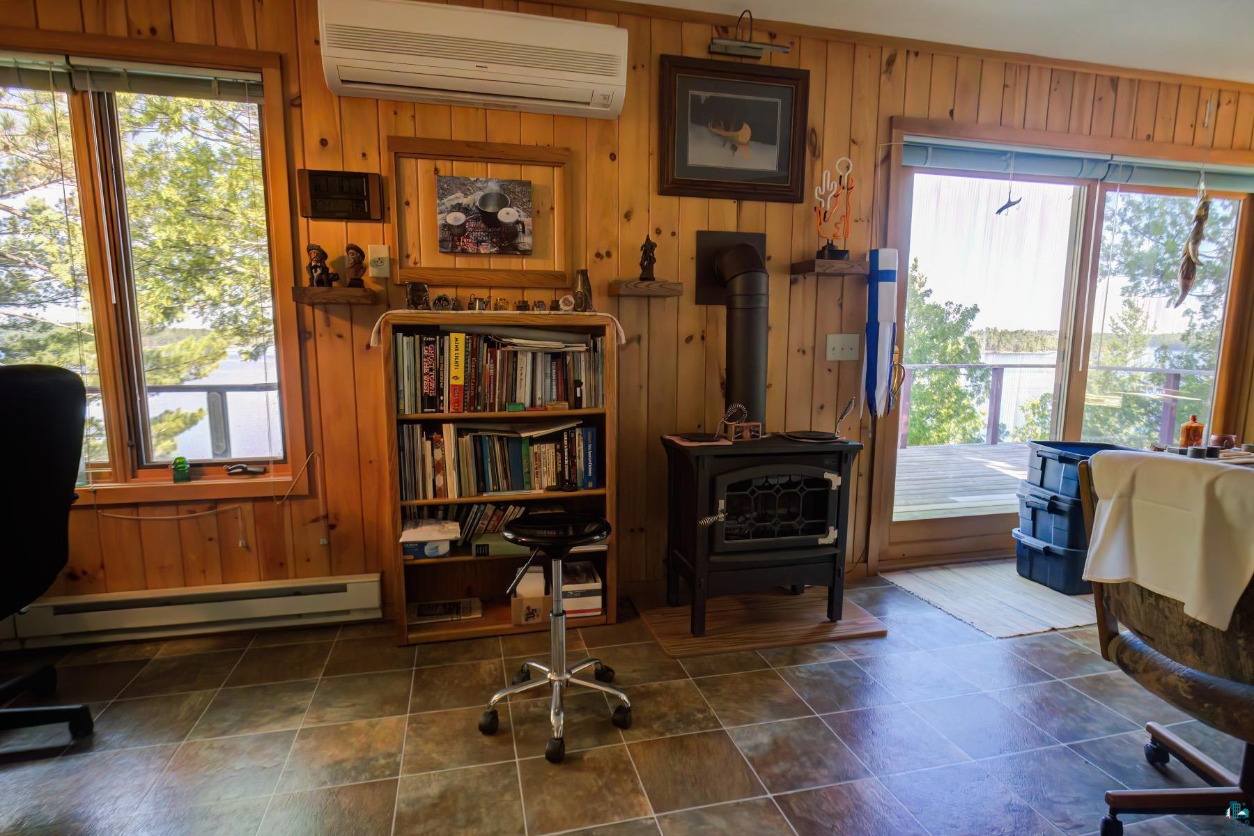 2811 Schaeffer Road Ely, MN 55731 - Photo 22 of 40 Wood paneling throughout, a built-in wood stove, and a wall-mounted air conditioning unit