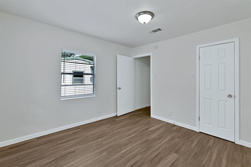 613 Cheyenne Road Dallas, TX 75217 - Photo 19 of 28 Expansive room featuring wood-finish flooring, light gray walls, a window with horizontal blinds, a ceiling-mounted light fixture, and two white paneled doors