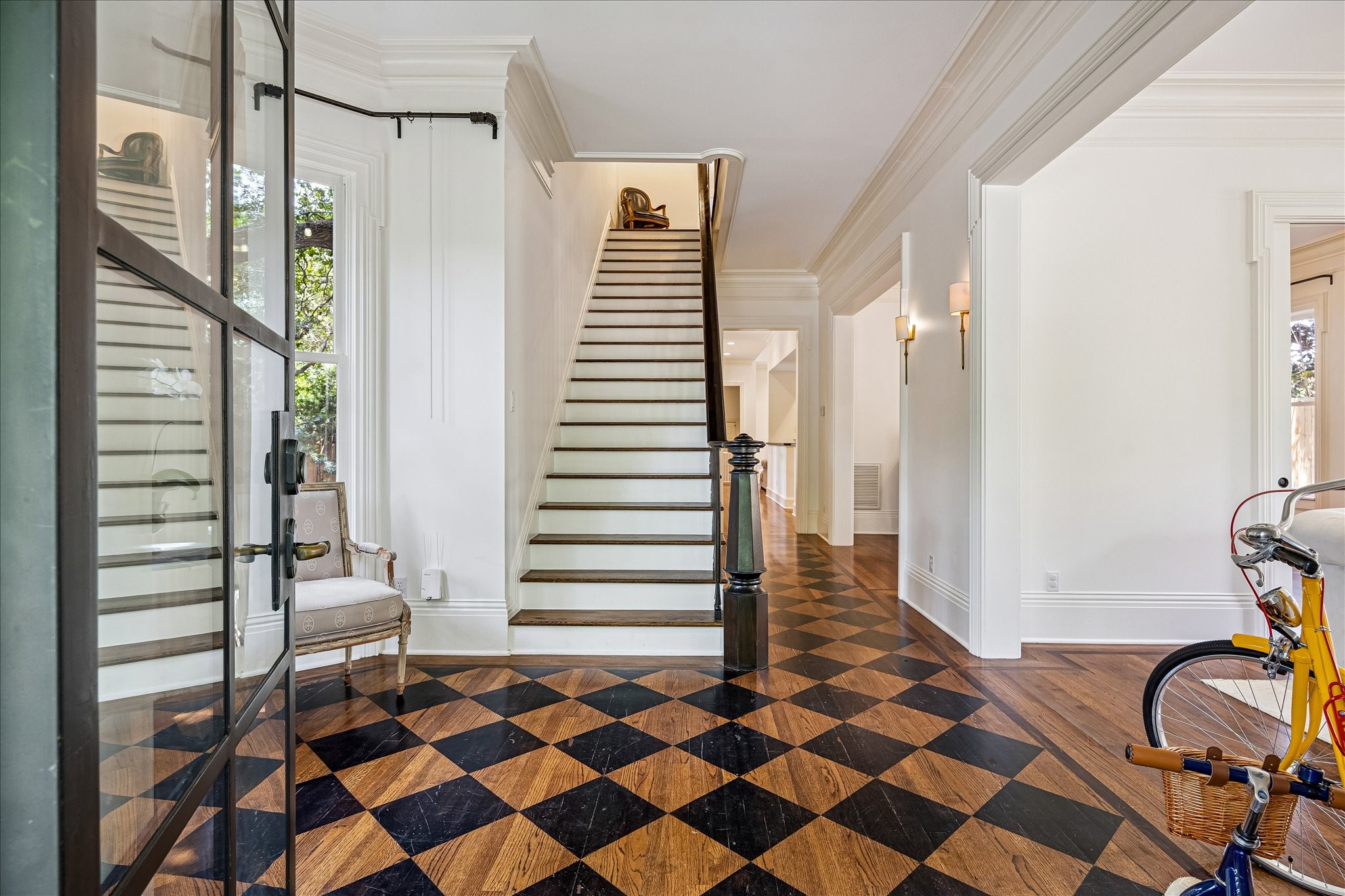 2368 Timber Lane Houston, TX 77027 - Photo 6 of 46 The iron double-paned front doors open to a grand entry showcasing custom walnut-inlay hardwood floors, striking architectural millwork, 12" baseboards, crown molding, and a dramatic staircase that immediately sets the tone for the home.