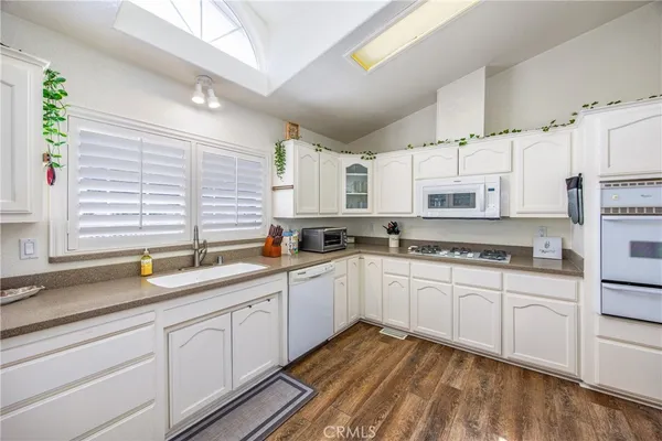 a kitchen with stainless steel appliances granite countertop white cabinets sink and window