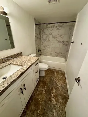 a bathroom with a granite countertop sink toilet and shower