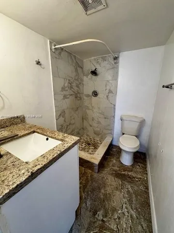 a bathroom with a granite countertop sink a toilet and shower