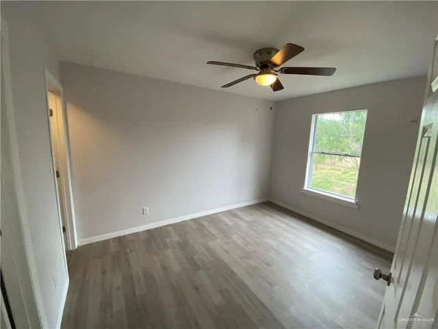 a view of an empty room with window and wooden floor