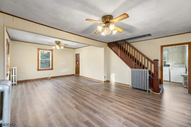 a view of an empty room with wooden floor and staircase
