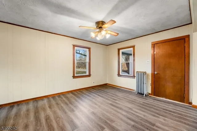 a view of an empty room with window and wooden floor