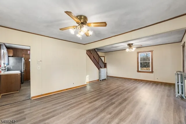 a view of an empty room with wooden floor and a ceiling fan