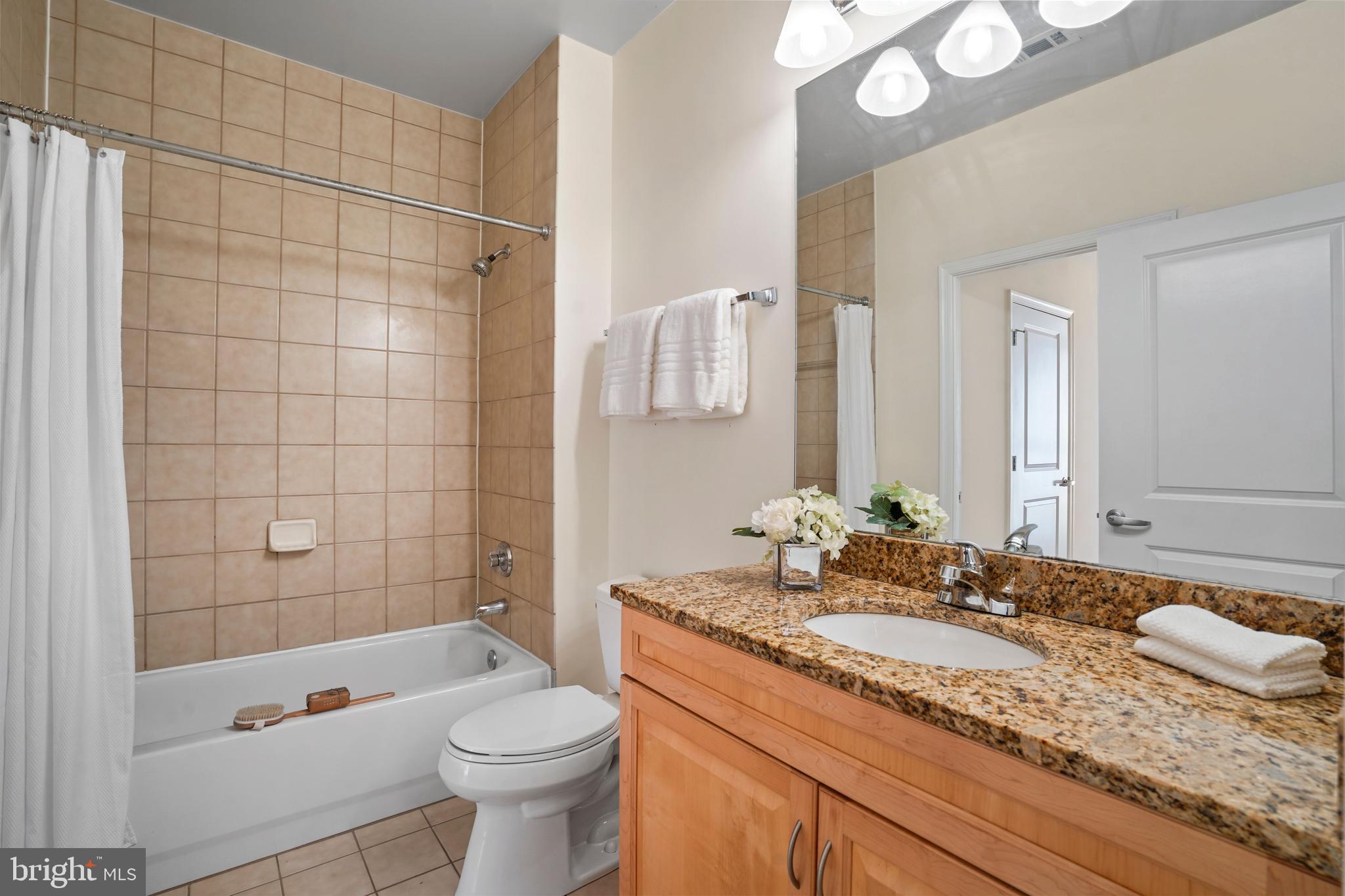 1111 25th Street Northwest, Unit 403 Washington, DC 20037 - Photo 15 of 24 a bathroom with a granite countertop sink a toilet a mirror a bathtub and shower