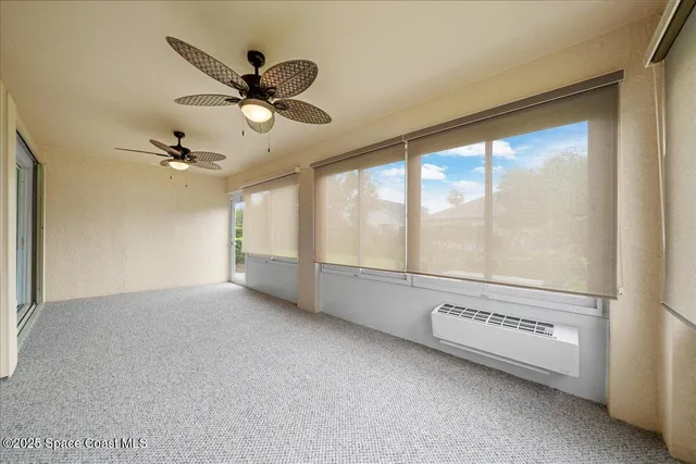 a view of an empty room with a ceiling fan and window