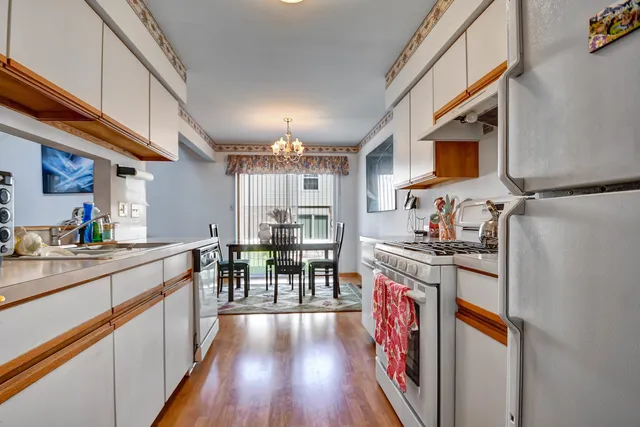 a kitchen with stainless steel appliances granite countertop a refrigerator a stove top oven a sink and dining table with wooden floor