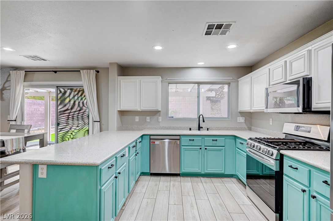 197 Kings Canyon Court Henderson, NV 89012 - Photo 11 of 39 Kitchen featuring stainless steel appliances, a peninsula, light countertops, blue cabinets, and light wood-style flooring