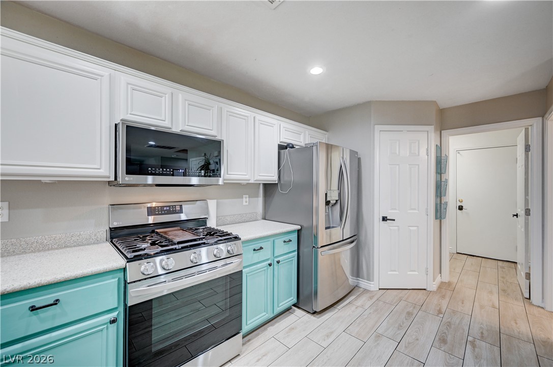 197 Kings Canyon Court Henderson, NV 89012 - Photo 13 of 39 Kitchen featuring stainless steel appliances, blue cabinetry, light countertops, light wood-type flooring, and recessed lighting