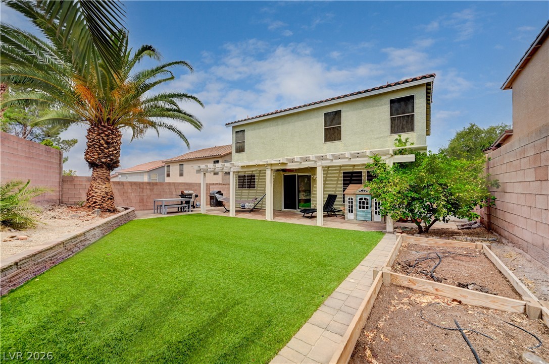 197 Kings Canyon Court Henderson, NV 89012 - Photo 35 of 39 Rear view of property with a pergola, a garden, a fenced backyard, a patio, and stucco siding