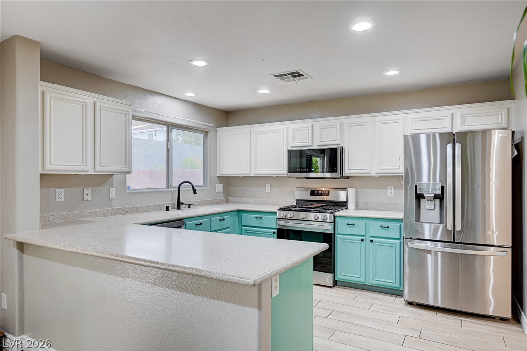 197 Kings Canyon Court Henderson, NV 89012 - Photo 9 of 39 Kitchen featuring stainless steel appliances, blue cabinetry, white cabinetry, a peninsula, and recessed lighting