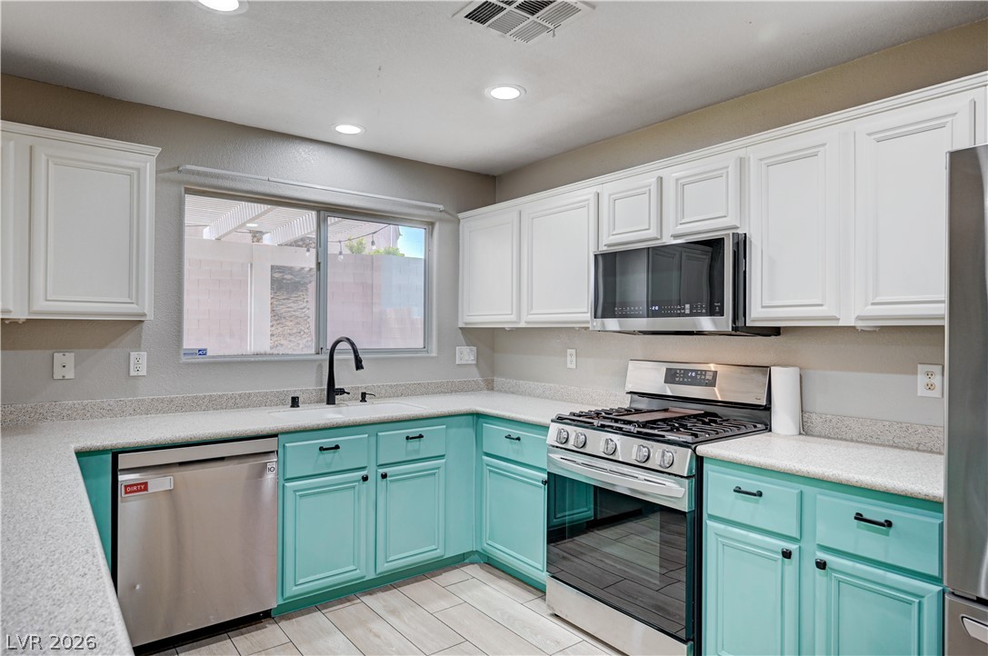 197 Kings Canyon Court Henderson, NV 89012 - Photo 10 of 39 Kitchen with appliances with stainless steel finishes, recessed lighting, blue cabinetry, light countertops, and white cabinetry