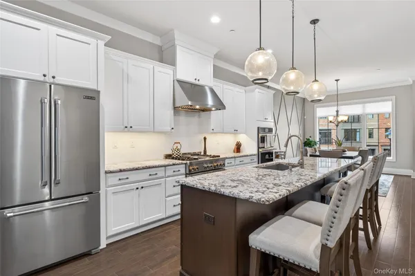 a kitchen with stainless steel appliances granite countertop a sink a stove a refrigerator and island