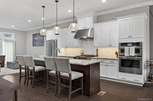 a kitchen with stainless steel appliances a stove a sink a microwave a refrigerator a dining table and chairs