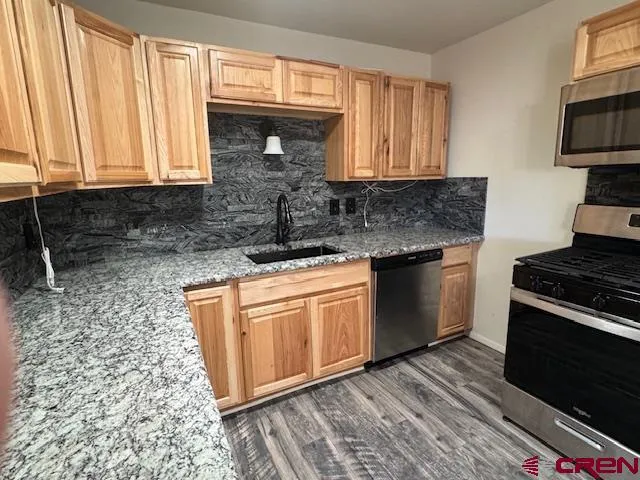 a kitchen with stainless steel appliances granite countertop a stove a sink and a microwave