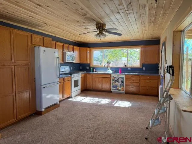 a kitchen with stainless steel appliances granite countertop a stove a refrigerator and a sink with wooden cabinets