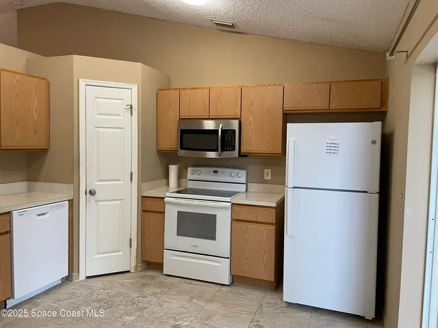 a white refrigerator freezer and a stove sitting inside of a kitchen