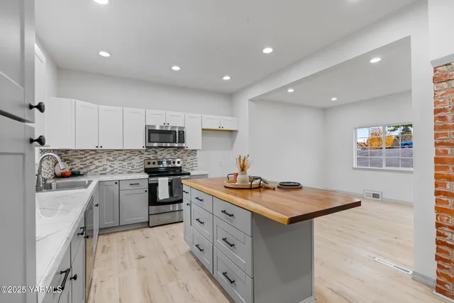 a kitchen with stainless steel appliances granite countertop a stove a sink dishwasher and a refrigerator with white cabinets