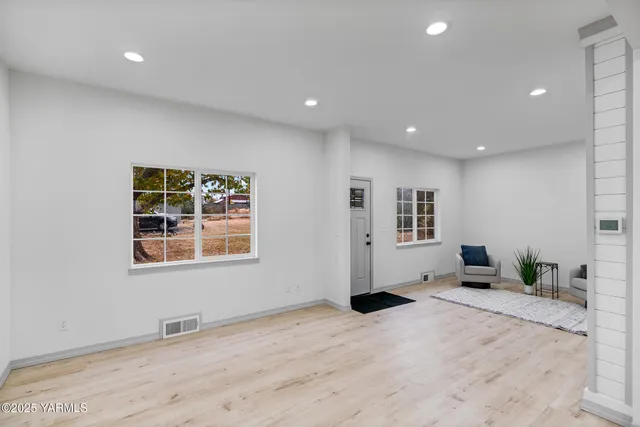 a view of empty room with wooden floor and windows