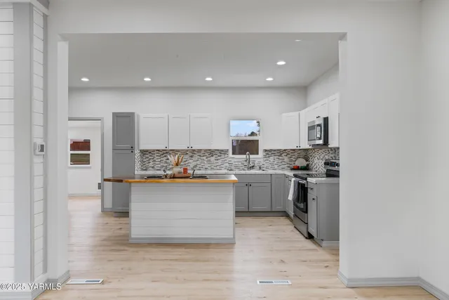 a kitchen with stainless steel appliances granite countertop a stove top oven a sink dishwasher and a refrigerator