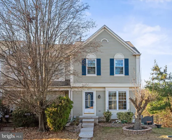 a front view of a house with plants and trees