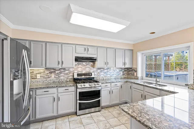 a kitchen with stainless steel appliances granite countertop a stove a sink dishwasher a refrigerator and cabinets with wooden floor