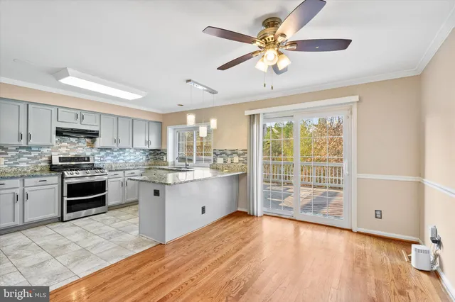 a kitchen with stainless steel appliances a stove a sink dishwasher a refrigerator with white cabinets and wooden floor