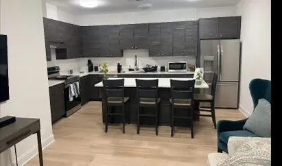 a kitchen with stainless steel appliances a table chairs and a refrigerator
