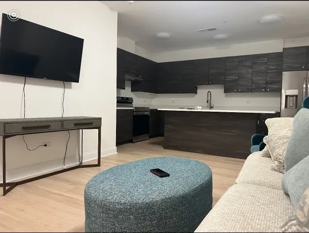 a living room with stainless steel appliances kitchen island granite countertop furniture and a flat screen tv
