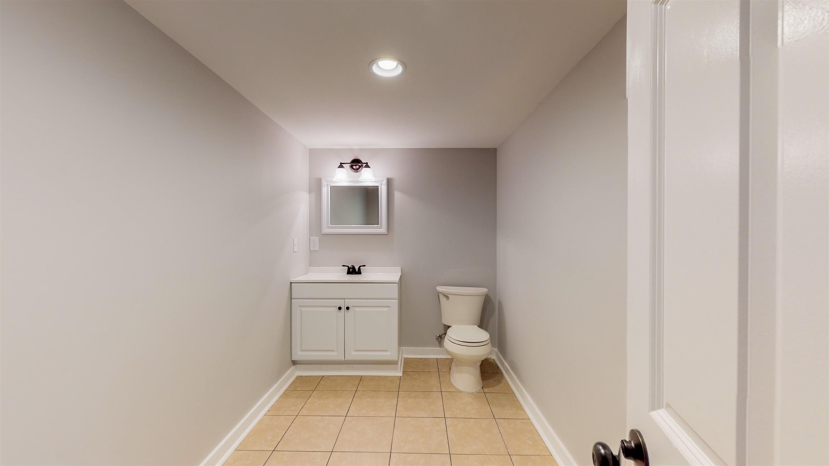 110 Green Acres Road Cottontown, TN 37048 - Photo 23 of 28 a bathroom with a toilet a sink a mirror and a shower