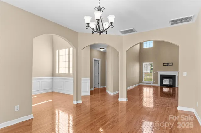 a view of a hallway with wooden floor and a chandelier