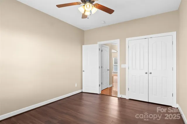 an empty room with wooden floor and a ceiling fan