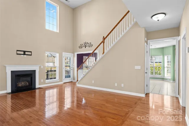 a view of an empty room with wooden floor and a fireplace