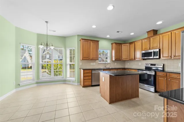 a large kitchen with stainless steel appliances granite countertop a refrigerator a stove top oven a sink and a granite counter tops