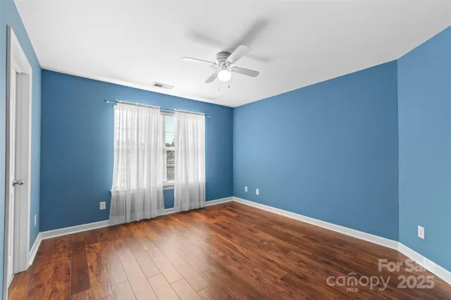 an empty room with wooden floor fan and windows