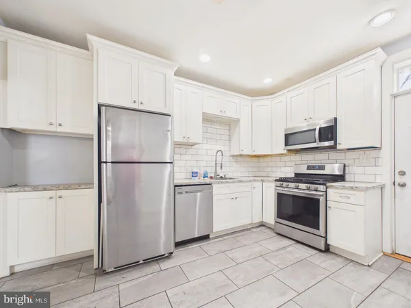 a kitchen with stainless steel appliances granite countertop a refrigerator sink and stove