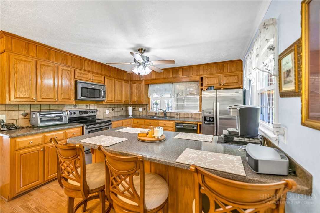 346 Piney Creek Road Lansing, NC 28643 - Photo 8 of 24 a view of a kitchen with kitchen island granite countertop a large window cabinets and stainless steel appliances