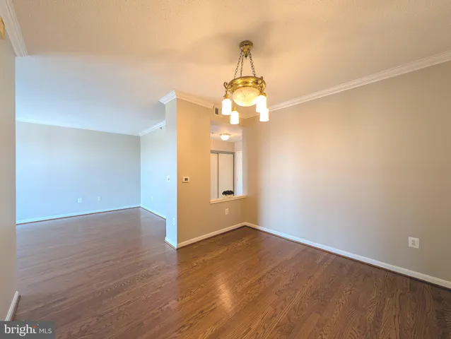 a view of a hallway with wooden floor and chandelier