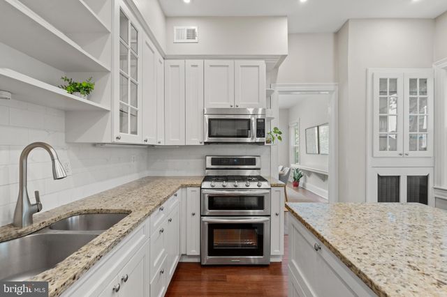 a kitchen with granite countertop a sink stainless steel appliances and cabinets