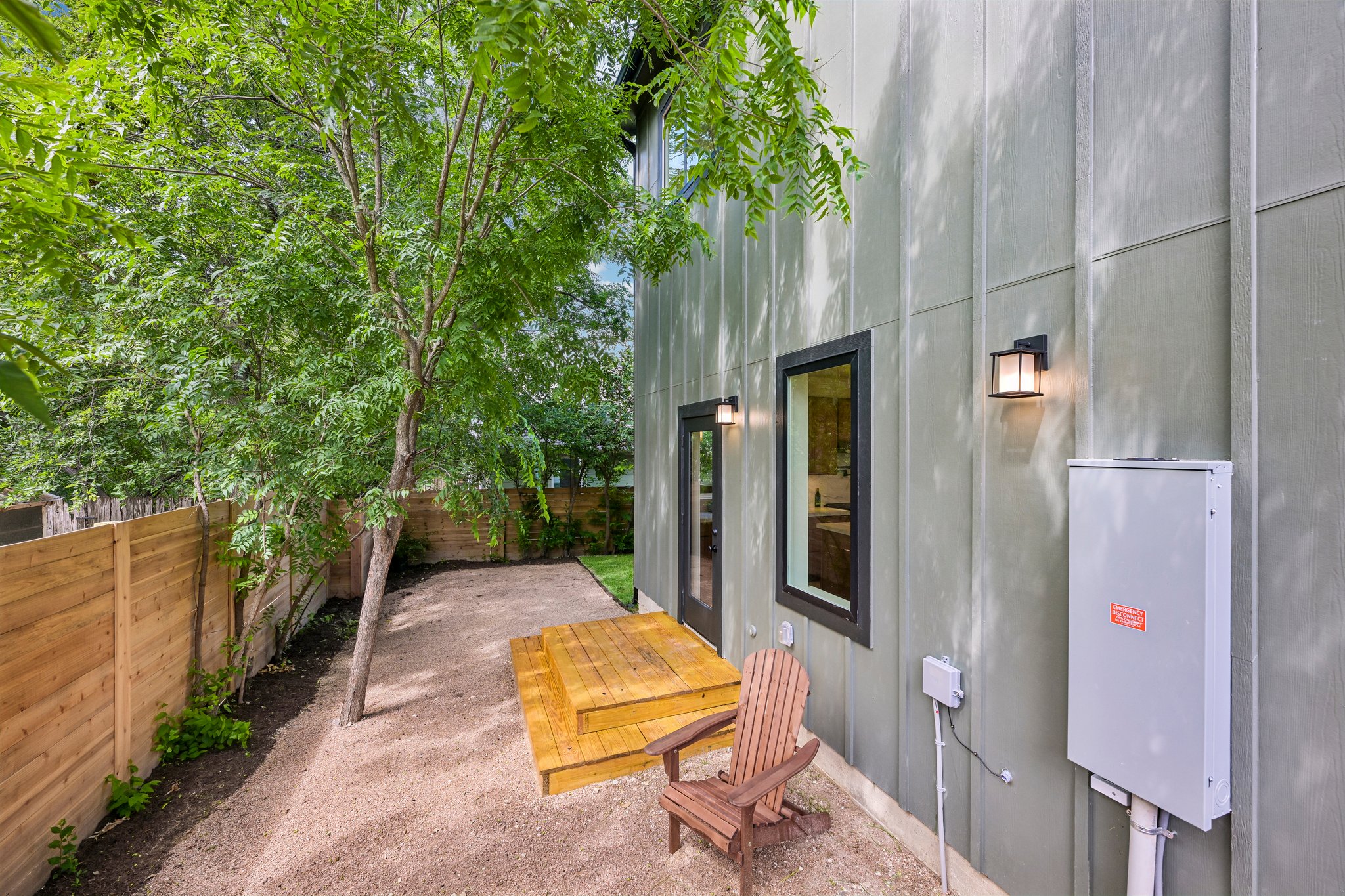 513 West Odell Street, Unit B Austin, TX 78752 - Photo 35 of 38 A private, fenced outdoor space with natural landscaping, a wood deck, and modern exterior lighting.