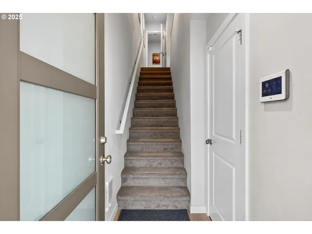 a view of a hallway with stairs and wooden floor
