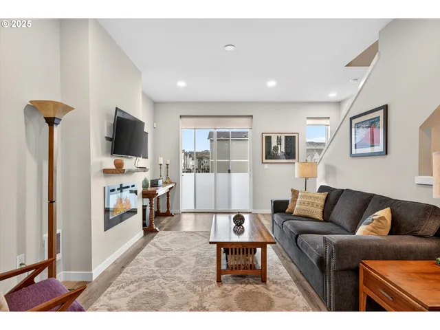 a living room with furniture a flat screen tv and a refrigerator