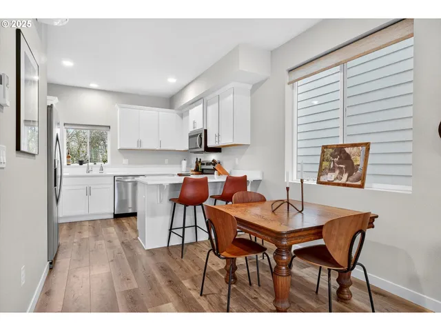 a open dining room with stainless steel appliances kitchen island granite countertop a dining table chairs and a refrigerator