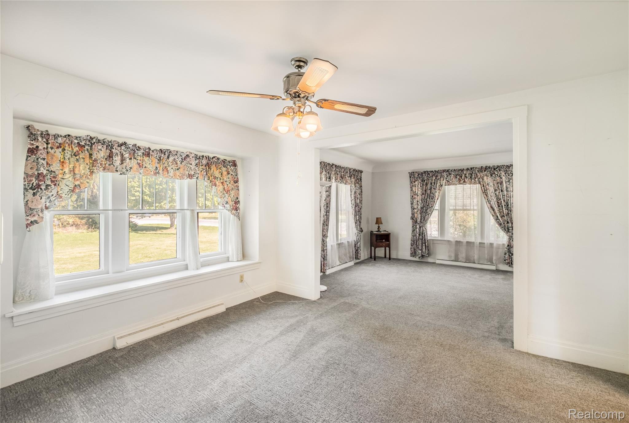 5447 North State Road Davison, MI 48423 - Photo 5 of 29 Unfurnished room with baseboard heating, carpet flooring, and a ceiling fan