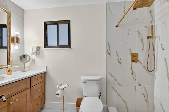 a bathroom with a granite countertop sink toilet and shower