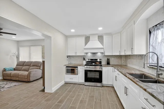 a large kitchen with stainless steel appliances granite countertop a sink a stove a refrigerator and cabinets